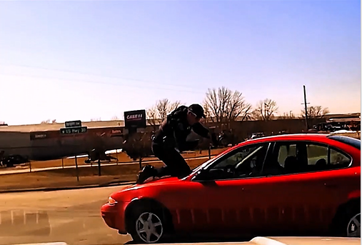 A police officer suffered a broken back after clinging to the roof of a suspect's vehicle that was fleeing after being ordered to stop.