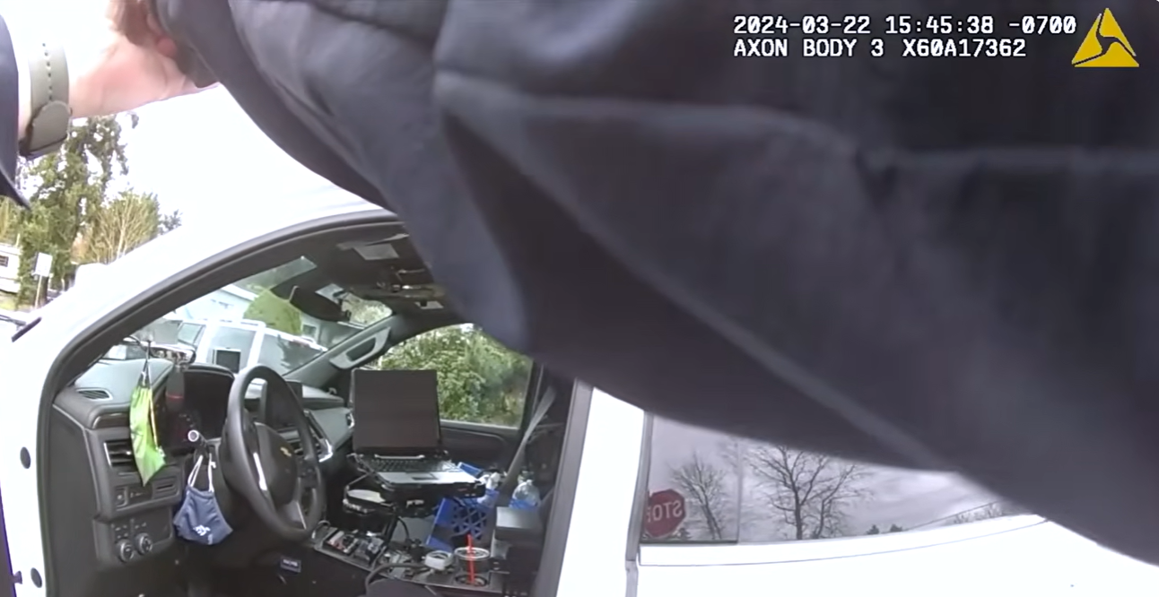 Real March 22, 2024 body-camera frame showing officers working around a patrol vehicle during the Pierce County investigation